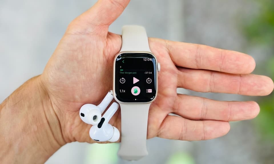 POV picture of Apple Watch and AirPods in the hand of a runner with the Snipd podcast app visible on the watch face.